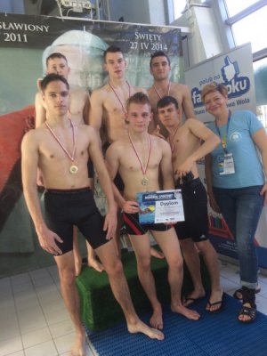 Uczniowie na podium zawodów pływackich na basenie.