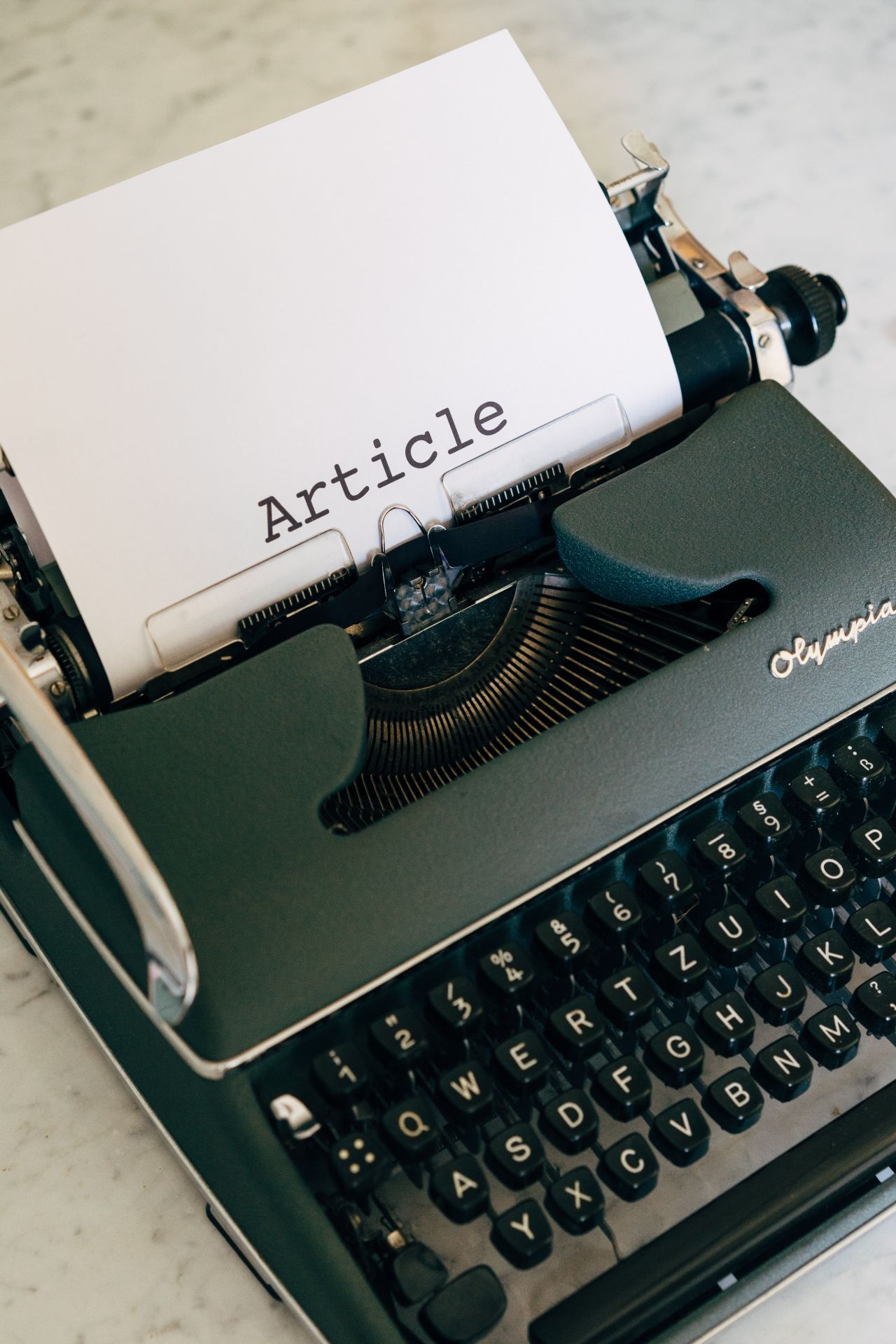 Na zdjęciu maszyna do pisania, na włożonej kartce papieru napis "Article". Zdjęcie autorstwa Markus Winkler z Pexels